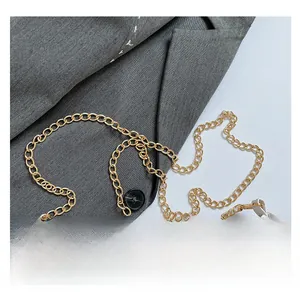 Detail of durable gold chunky chain strap on a white woven texture underarm bag