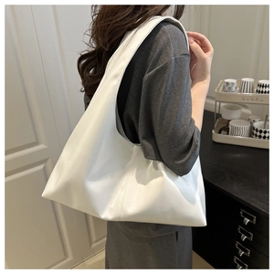 White minimalist Hobo shoulder bag in glossy leather worn by a model in a modern home setting