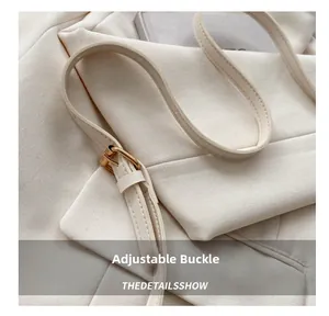 Détail de la bandoulière réglable avec boucle dorée sur un sac cabas en toile crème