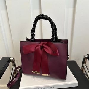 Burgundy mini tote bag with satin bow and black woven handle for a feminine look