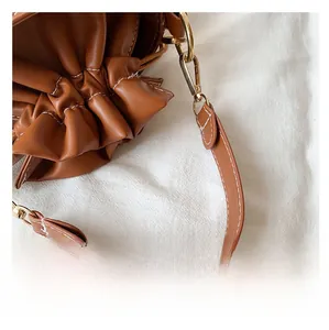 Gros plan détaillé du sac seau marron caramel avec surpiqûres blanches et boucles dorées