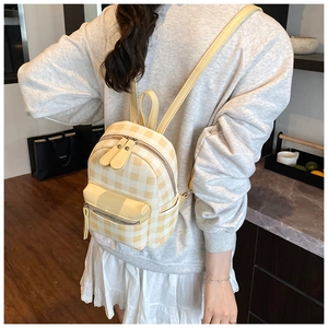 Nahaufnahme eines gelb-cremefarbenen Mini-Rucksacks mit Karomuster und Trägern am Model