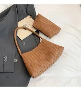 Detail of woven brown shoulder bag and pouch set with leather intrecciato texture
