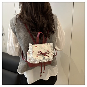 Detail view of bow backpack with lace trim and heart pendant on a female model