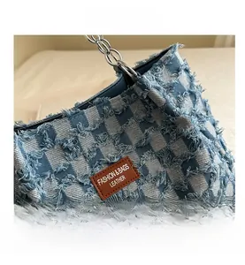 Close-up of denim checkerboard tote bag with distressed edges and metal chain strap
