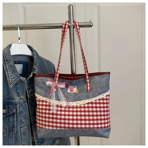 Detailansicht der Spitze, rot-weißen Karoschleife und Kirsch-Patch auf der Jeans-Tasche