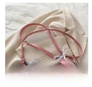 Detail of pink Y2K crossbody bag with silver heart buckle and blue plaid scarf