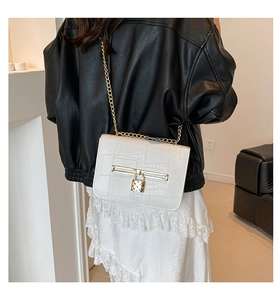Detail of white crocodile pattern shoulder bag with gold chain and metal buckle closure