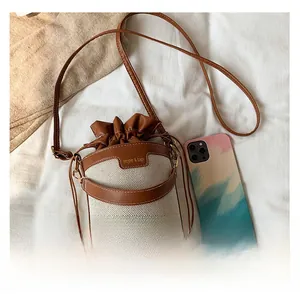 Détail du sac seau en toile avec finitions en cuir marron et fermeture à cordon
