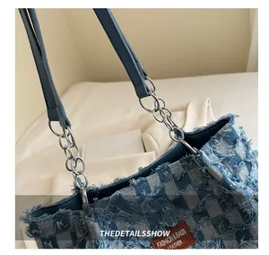Detail of denim checkerboard tote bag with metallic chain links and leather tag