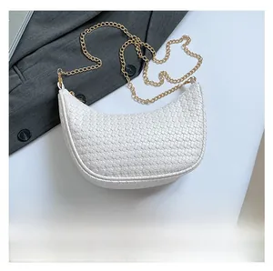 Detail of white woven crescent bag featuring fine cross-weave texture and gold chain