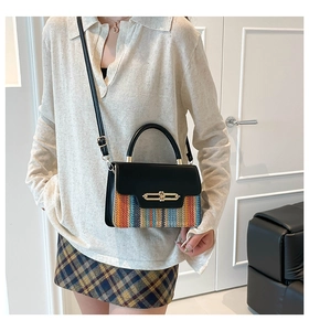 Detail of color-block woven straw bag with black leather flap and gold metal clasp