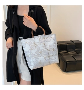 Detail of elegant jacquard tote bag with natural bamboo handles and floral patterns