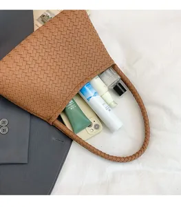 Detail of brown woven tote showing large capacity with phone and cosmetics