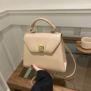 Minimalist beige trapezoid handbag with gold turn-lock and elegant curved top handle