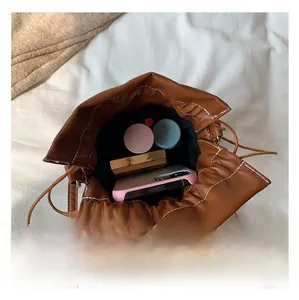Internal view of brown bucket bag showing capacity for phone and cosmetics