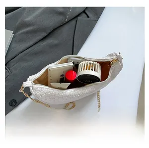 Spacious interior of white woven crescent bag showing daily essentials and gold chain