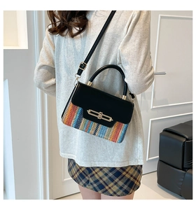 Detail shot of the colorful woven texture and gold buckle on a stylish black leather handbag