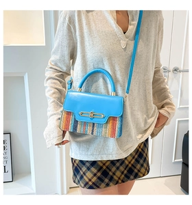 Detail of multi-color woven crossbody bag with blue flap and gold turn-lock closure