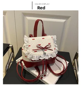 Detail of red and cream ballet-style backpack with lace trim and heart pendant