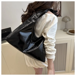 Chic black glossy hobo bag shown in a stylish home setting worn as a shoulder bag