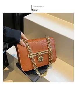 Close-up of brown crocodile texture leather bag with gold chain and metal lock detail