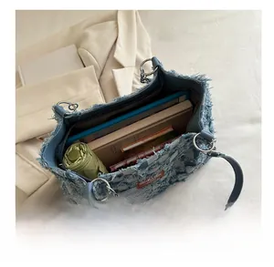 Detail shot of large denim tote bag interior showing spacious capacity for books and umbrella