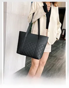 Gros plan d'un sac cabas noir en cuir matelassé porté avec un élégant blazer beige