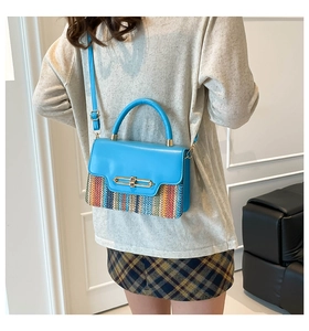Detail of blue PU leather handbag with woven base and gold metal lock on a model