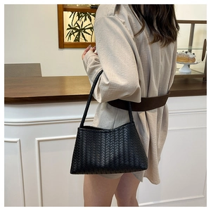 Detail of black woven leather texture and handle on a large vintage hobo shoulder bag