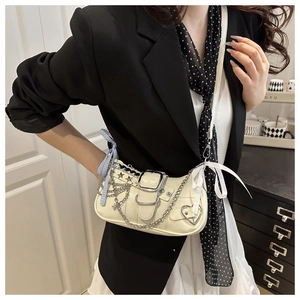 Detail of off-white shoulder bag with silver chains, star studs and blue bow accents