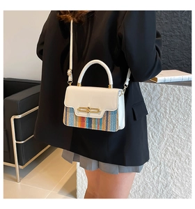 Detail view of woven contrast shoulder bag with golden twist lock and adjustable strap