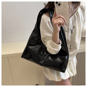 Glossy black large tote bag with wide shoulder strap shown in a mirror selfie display