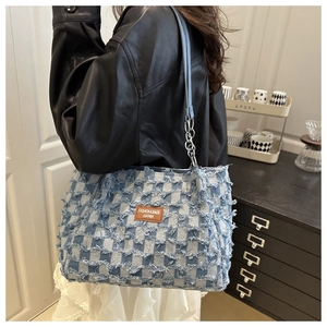 Macro view of checkered denim tote with fringe details and leather fashion label