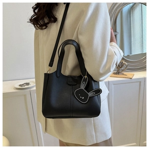 Détail d'un sac seau en cuir noir avec pendentif lapin et finitions élégantes