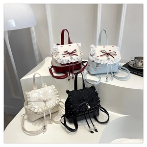 Detail of four lace-trimmed mini backpacks in burgundy, blue, beige and black colors