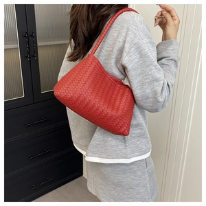 Detailed view of red woven shoulder bag in crescent shape with Intrecciato craftsmanship