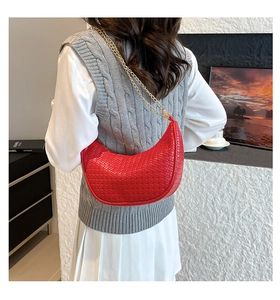 Close-up of red woven crescent hobo bag with gold chain strap on a fashion model