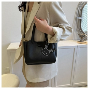 Sac seau en cuir noir avec breloque lapin assorti à un blazer beige élégant