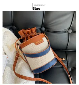 Close-up of drawstring bucket bag with beige canvas and blue leather contrast stitching