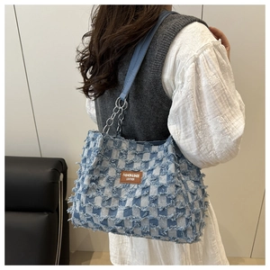 Détail du cabas en denim à carreaux bleus avec bords effilochés et bandoulière en chaîne