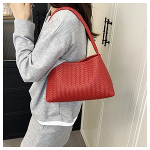 Detail of red hand-woven leather shoulder bag styled with a grey casual outfit