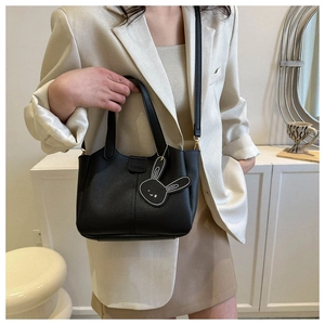 Sac à main chic en cuir PU noir porté par un mannequin avec pendentif lapin et détails mode