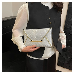 Détail de la pochette enveloppe argentée avec texture à écailles et bordure dorée