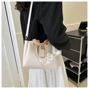Détail d'un sac cabas crème chic avec des anses marron et un charmant porte-clés lapin