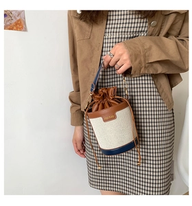 Detail view of canvas bucket bag with leather trim and drawstring closure on model