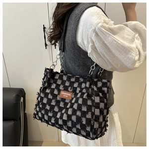 Detail of checkered tote bag with fringe texture and silver chain leather shoulder strap