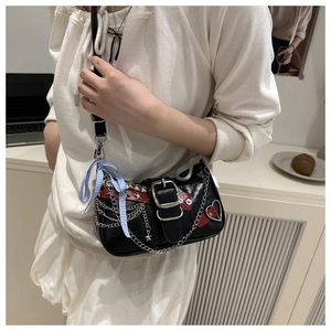 Detail of gothic punk shoulder bag with silver chains, star studs, and red leather straps