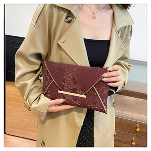 Détail de la pochette enveloppe bordeaux motif serpent avec bordure en métal doré