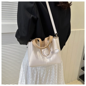 Sac fourre-tout beige avec charm lapin et bandoulière porté par un mannequin